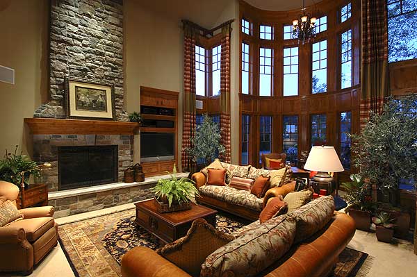 Great room with stone fireplace, large wood-trimmed windows, and multi-level seating areas.
