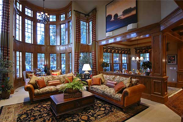 Living room with curved bay windows, wood paneling, two sofas, and a large patterned rug.