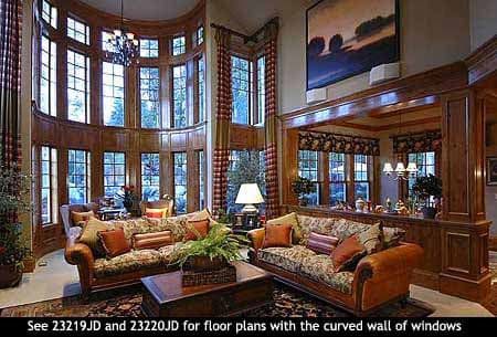 Great room with large curved wall of windows, wood paneling, and coffered ceiling detail.
