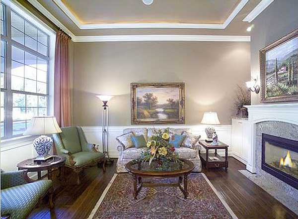 Interior view of a living room with a fireplace, large window, tray ceiling, sofa, chairs, and coffee table.