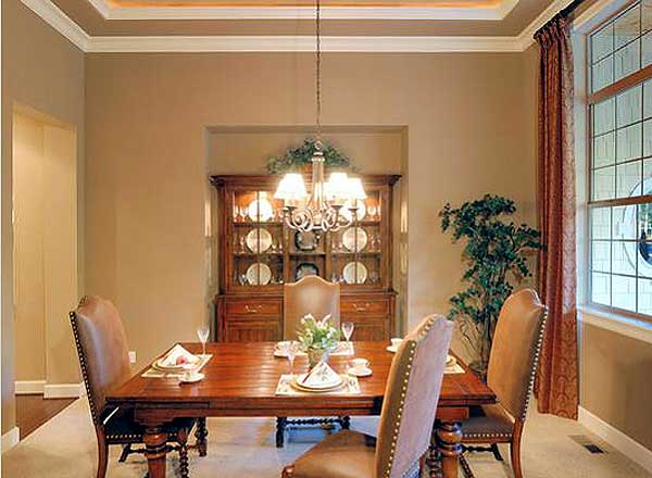Dining room with wood table, chairs, hutch, chandelier, and tray ceiling.