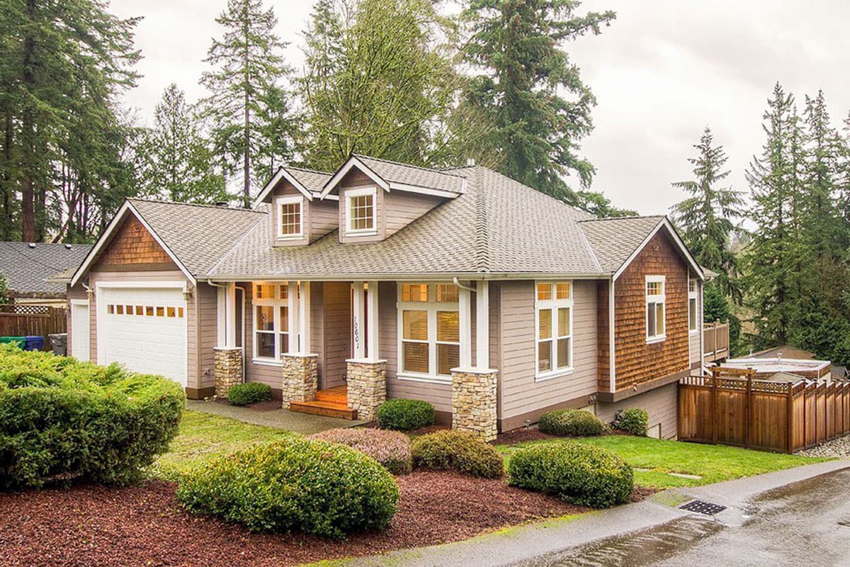 House plan exterior with Craftsman style. Features include gabled roof, stone-clad columns, and shake siding. Includes a front-facing garage.