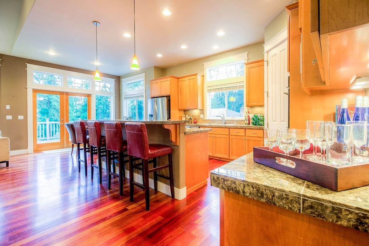 Open-concept kitchen with large island, wood cabinets, granite countertops, and glass-paneled doors.