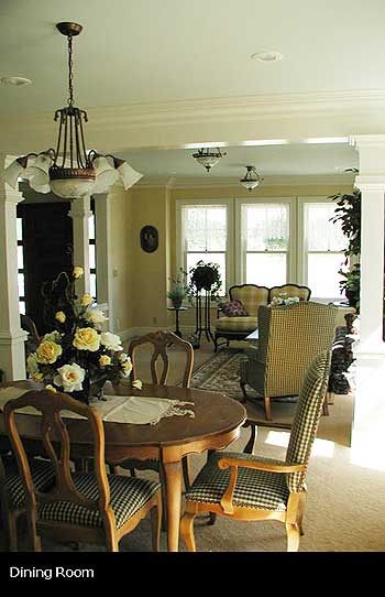 Dining room with wooden table and chairs, chandelier, and sitting area with sofa and armchair.