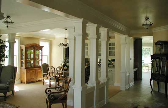 Interior view showing dining room with china cabinet, chairs, and decorative columns.