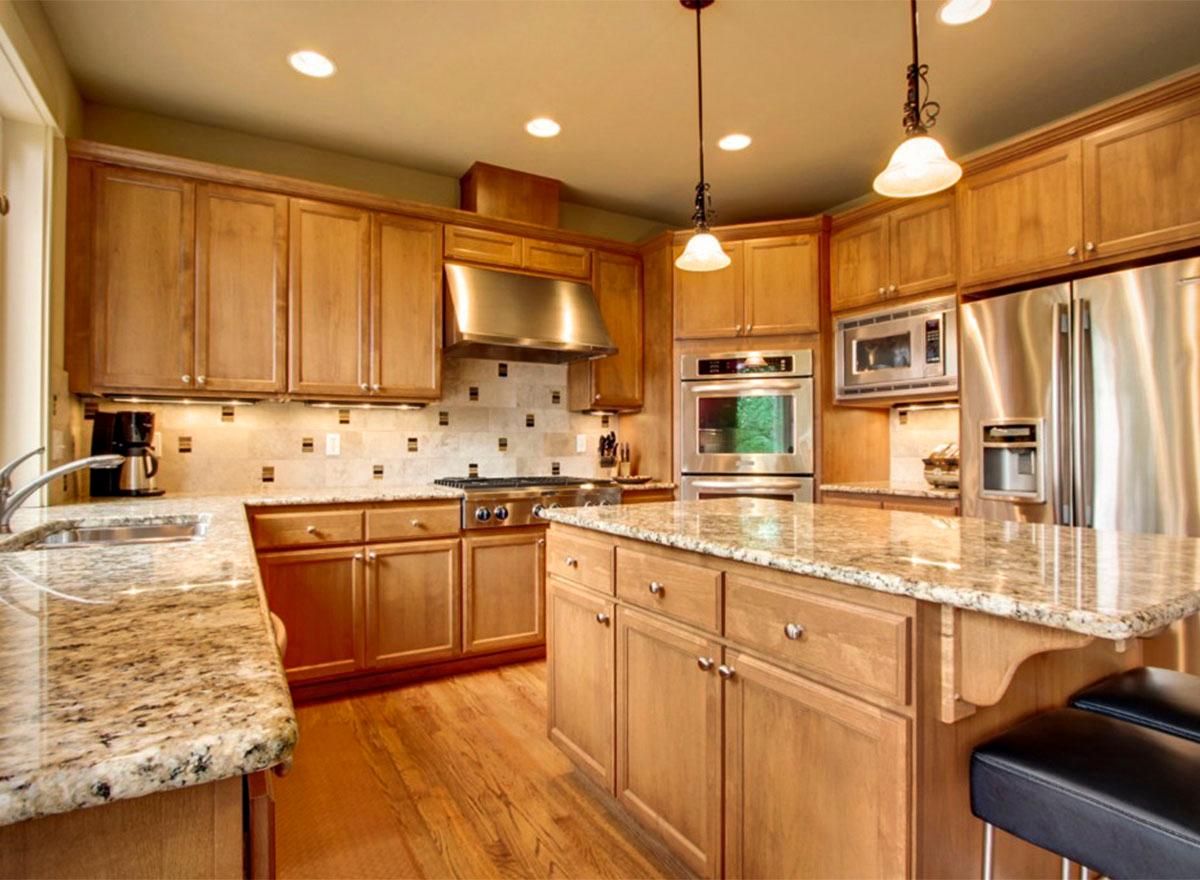 Kitchen with light wood cabinets, granite countertops, stainless steel appliances, and a central island.