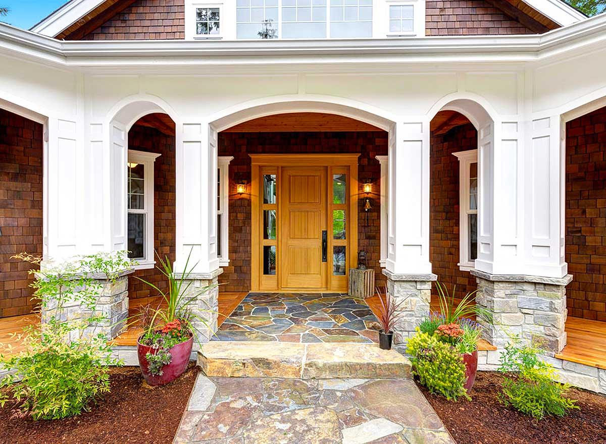 House plan exterior with arched portico, stone and wood facade, and prominent double entry doors.