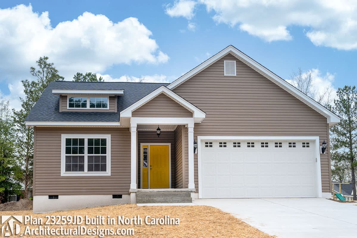 House plan exterior: one-story home with covered entry, dormer window, and attached two-car garage.