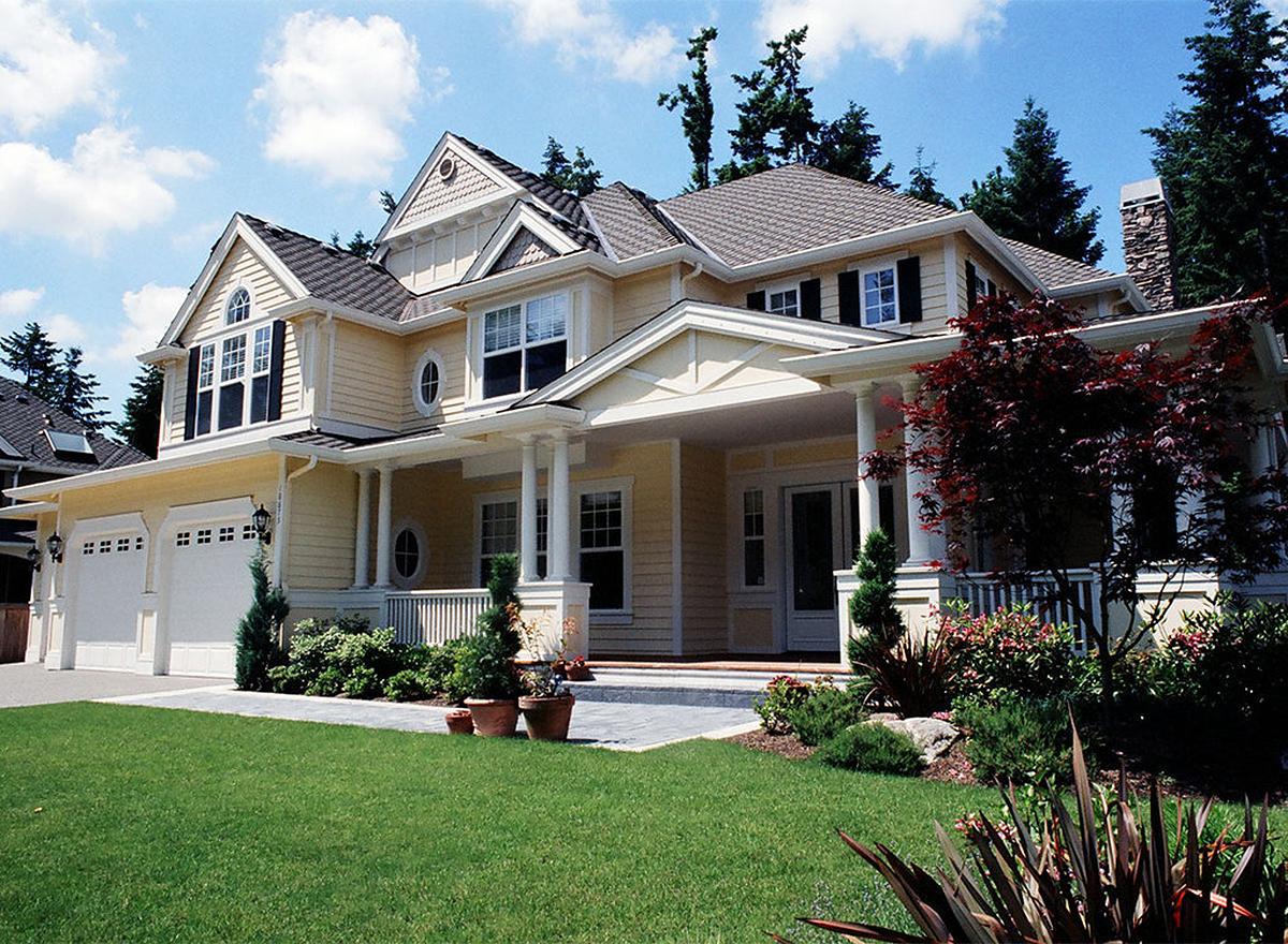 House plan exterior: two-story, gabled roof, prominent porch with columns, three-car garage.