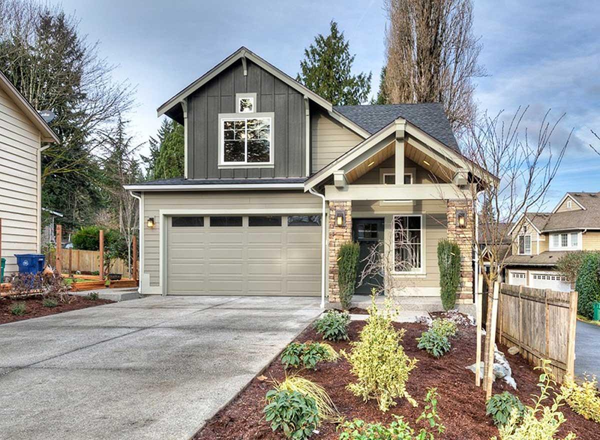 Two-story Modern Farmhouse exterior with board and batten siding, gabled roof, covered porch with exposed beams, and a two-car garage.