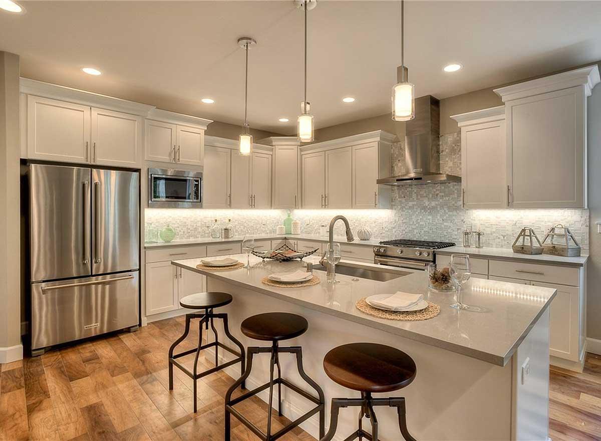 Kitchen with light gray cabinets, stainless steel appliances including a French door refrigerator, and a large island with seating.