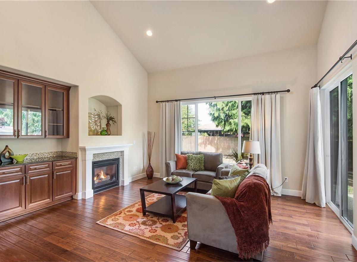 Living room with vaulted ceiling, fireplace, built-in cabinets, seating area, and large windows.