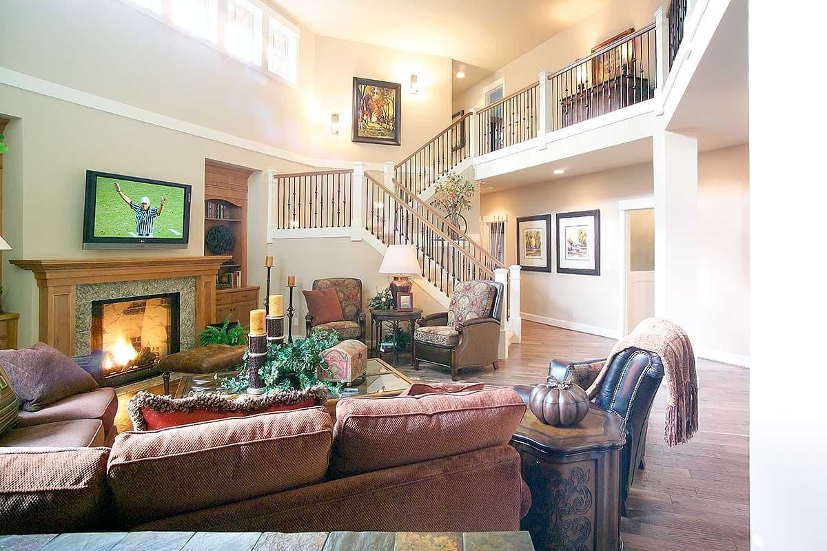 Great room with two-story ceiling, fireplace, media center, and open staircase with railings.
