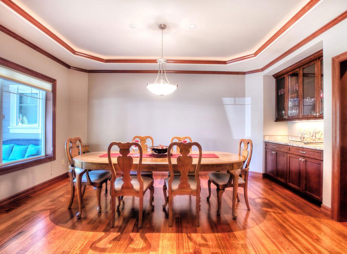 Dining room interior with oval table, six chairs, decorative molding on ceiling, and built-in cabinetry.