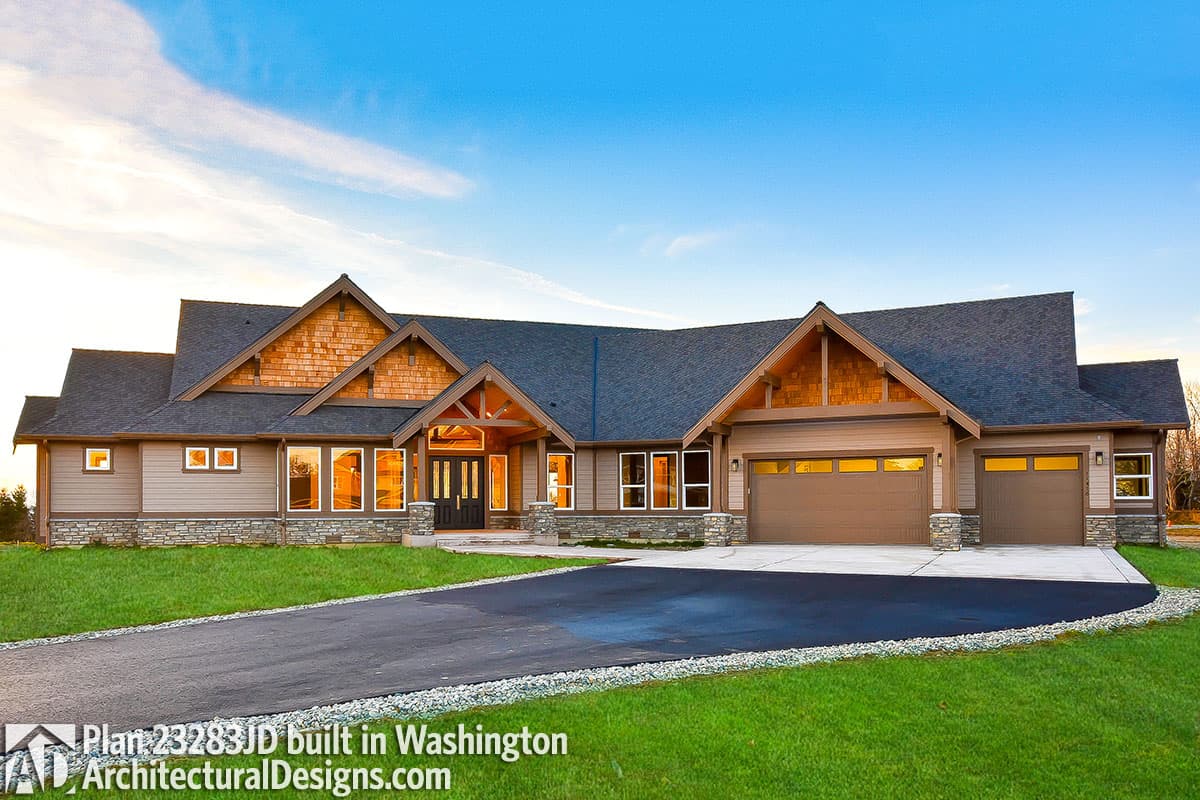 House plan exterior: Ranch style, prominent gables with wood shake siding, covered entry with exposed beams, and a three-car garage.