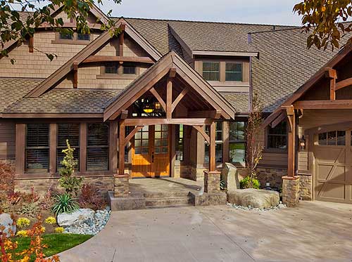 Craftsman style house plan exterior with a prominent timber-framed entryway, multiple gables, dormers, and an attached garage.