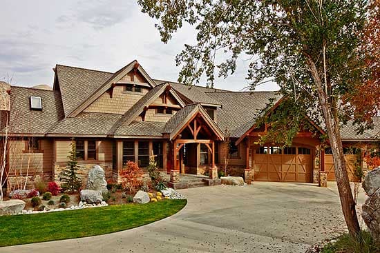 Craftsman style house plan exterior with multiple gables, wood siding, stone accents, covered entry, and double garage.