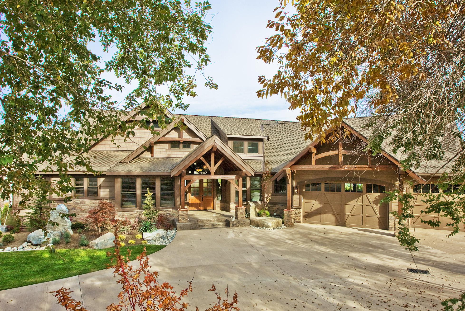 Craftsman style house plan exterior with wood shingle siding, gabled rooflines, exposed beams, and a triple garage.