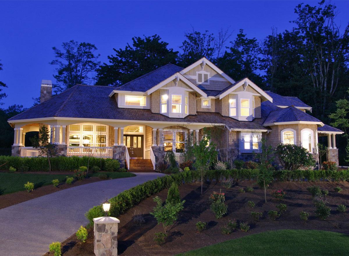 House plan exterior featuring a wraparound porch, stone accents, multiple gables, and a dormer.