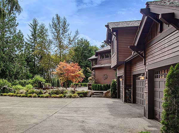 House plan exterior with wood siding, multiple gables, and a three-car garage with carriage-style doors.