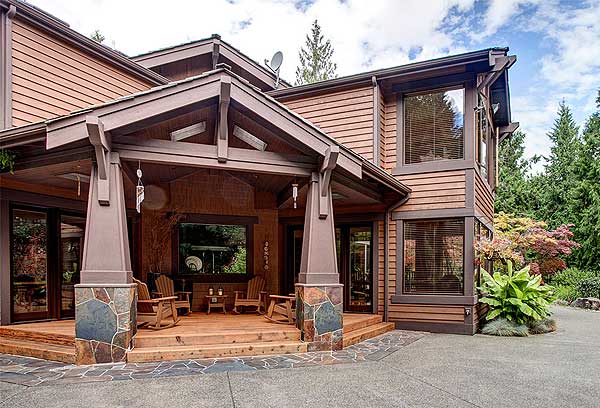 House plan exterior: Modern lodge style with covered porch, stone-clad columns, exposed beams, and horizontal siding.