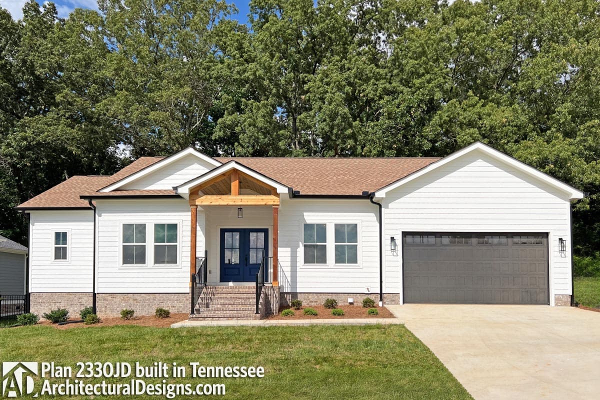 House plan exterior: Ranch style, white siding, prominent gable entry with timber accents, and attached two-car garage.