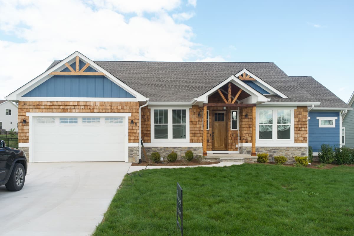 House plan exterior with Craftsman style. Features include a front-facing garage, gables, exposed rafter tails, and a covered front entry.