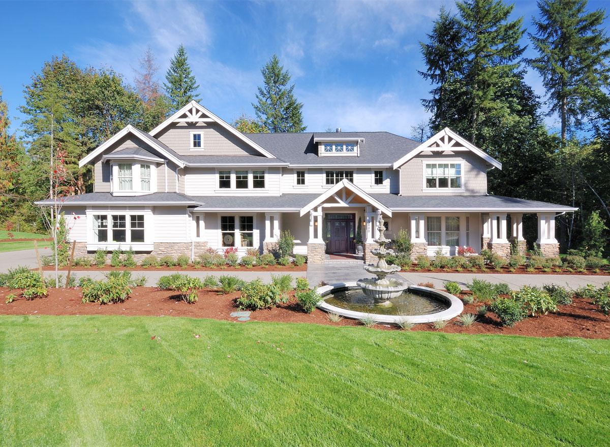 House plan exterior of a two-story home with a wraparound porch, gables, dormers, and a central entrance with a fountain.