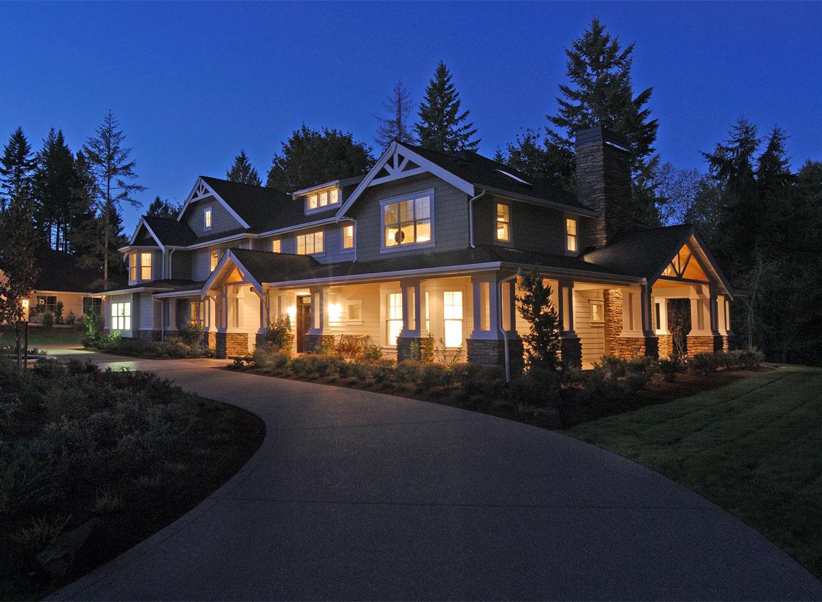 House plan exterior: two-story home with wrap-around porch, multiple gables, dormer windows, and stone chimney.