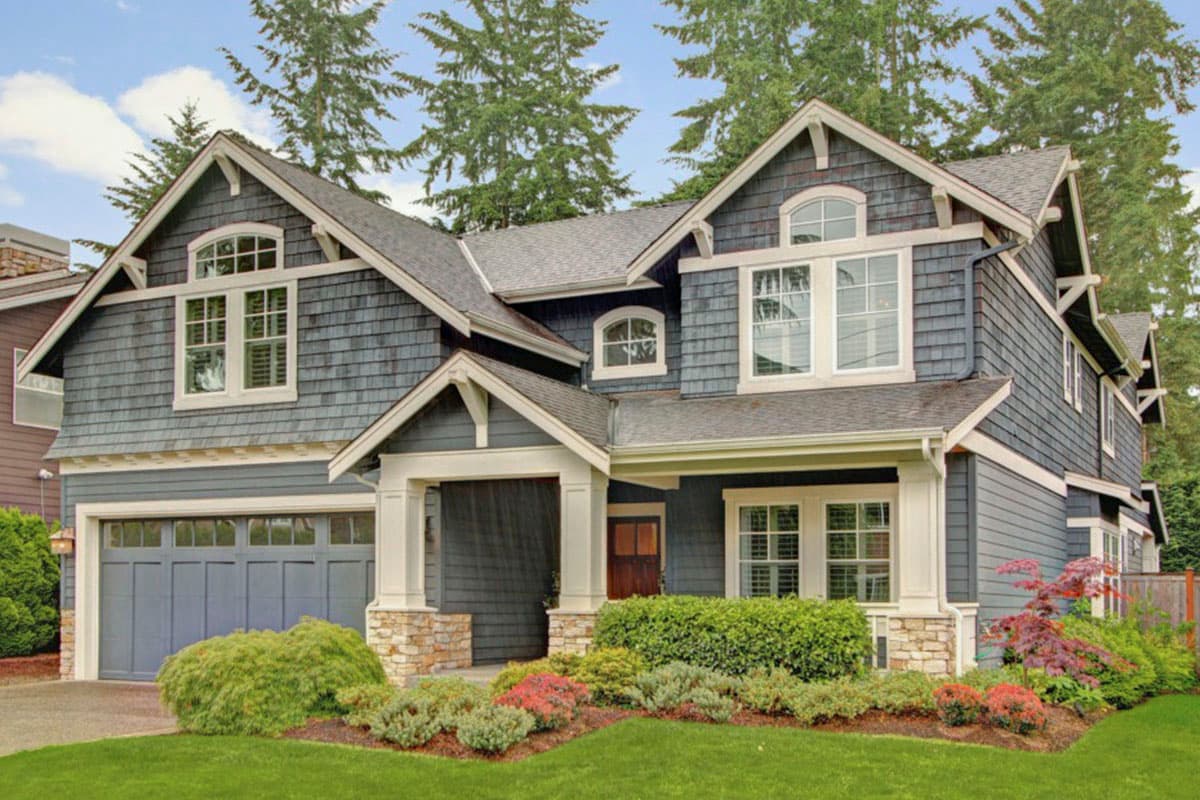 Craftsman house plan exterior with two stories, gabled roof, covered porch, dormers, and an attached garage.