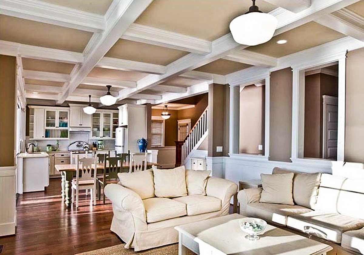 Interior view of a living area and kitchen with coffered ceiling, dining table, and seating area.