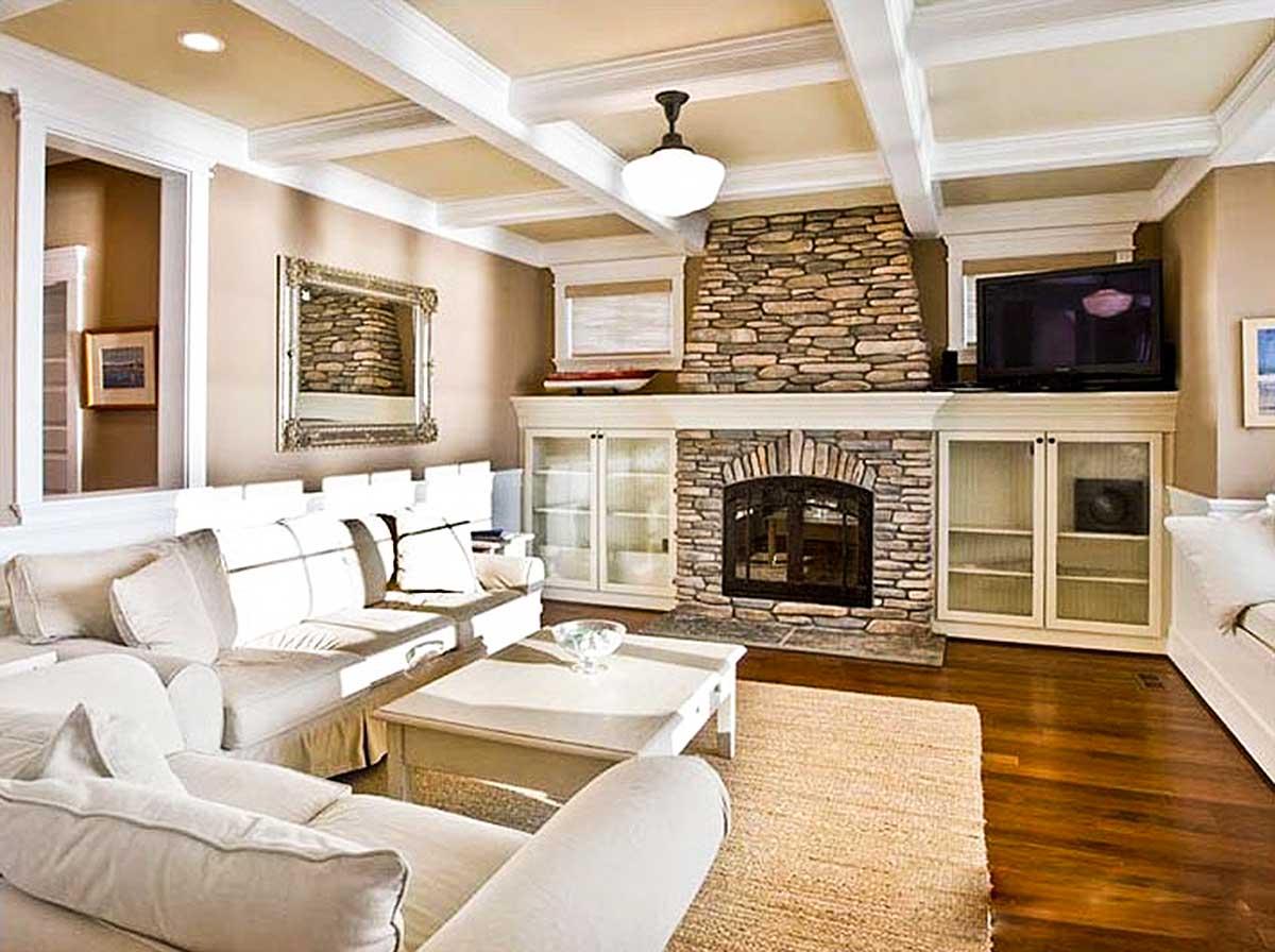 Interior view: Living room with stone fireplace, coffered ceiling, built-in cabinetry, and large sectional sofa.