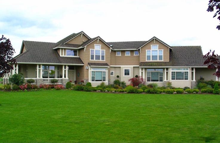 House plan exterior: two-story home with covered front porch, multiple gables, dormers, and stone accents.