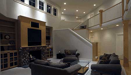 Interior view of a living room with stone fireplace, built-in shelving, and a split staircase.