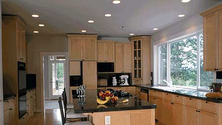 Kitchen with light wood cabinets, granite countertops, island with seating, and large bay window.