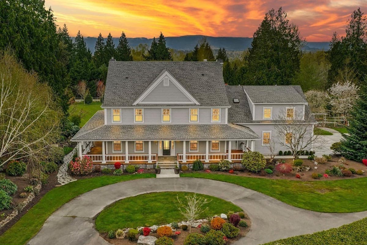 Two-story house plan exterior with wrap-around porch, gabled dormers, and a circular driveway.