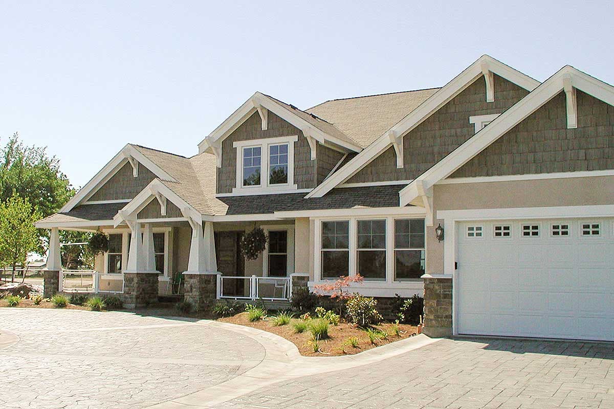 Craftsman style house plan exterior with wide eaves, decorative brackets, stone accents, covered porch, and attached garage.