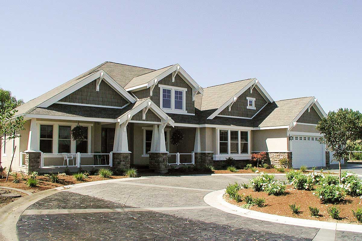 Craftsman style house plan exterior with covered front porch, gables, dormers, stone accents, and attached garage.