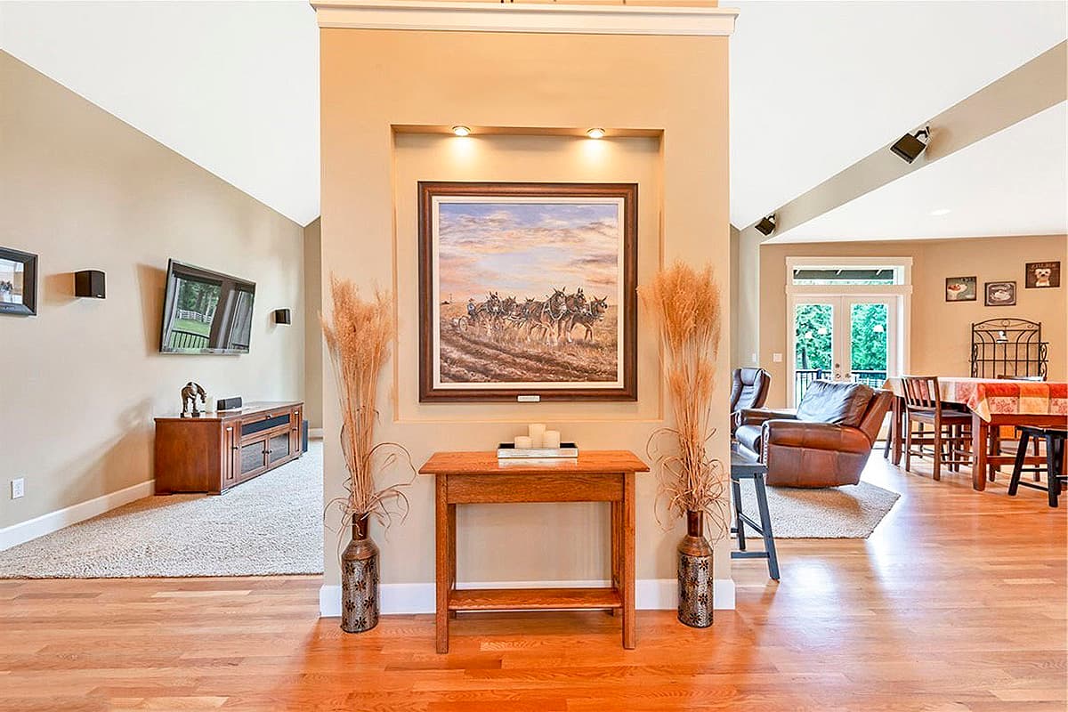 Interior view showing a great room with vaulted ceiling, entertainment center, and dining area with double doors.