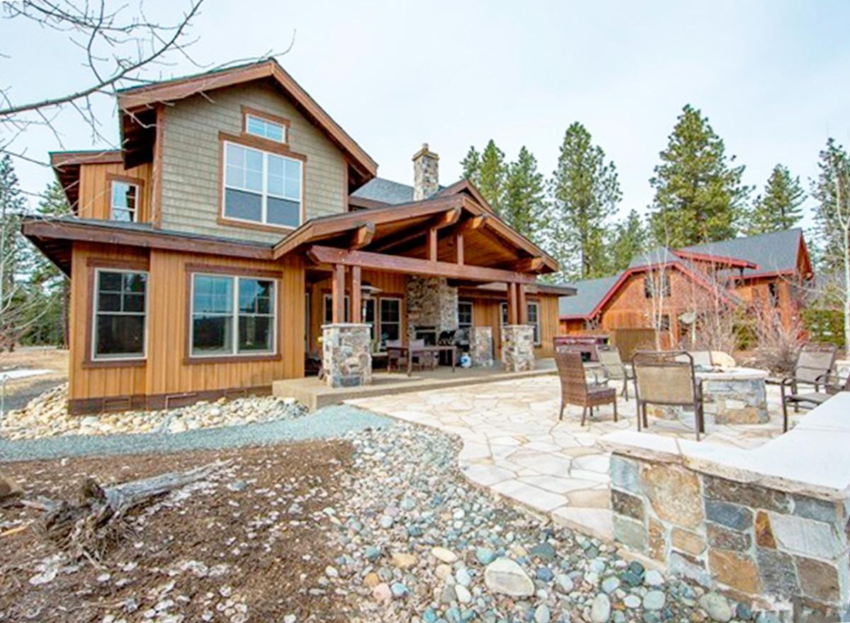 House plan exterior: Craftsman style, two stories, wood siding, stone accents, covered porch with stone fireplace, and stone pillars.