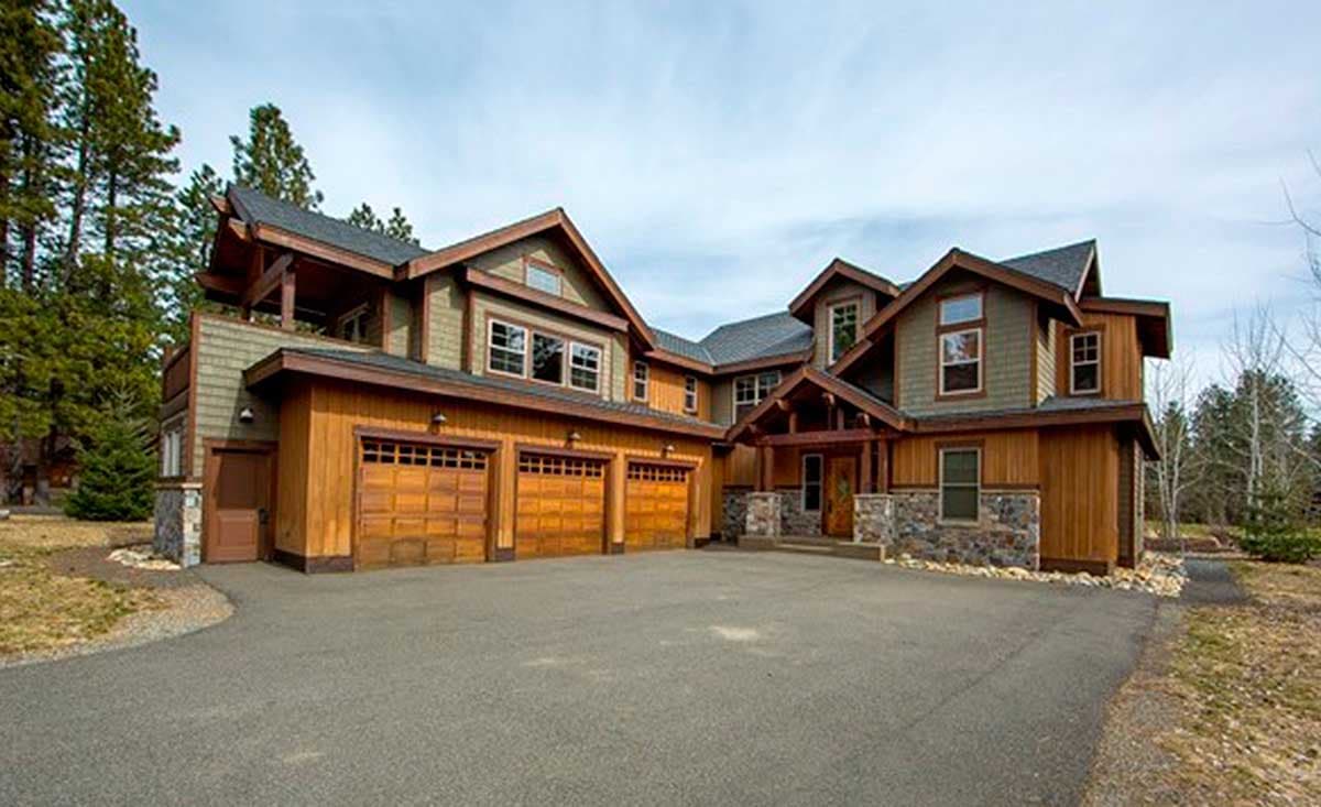 House plan exterior: Modern lodge style with a three-car garage, stone accents, and prominent gables.