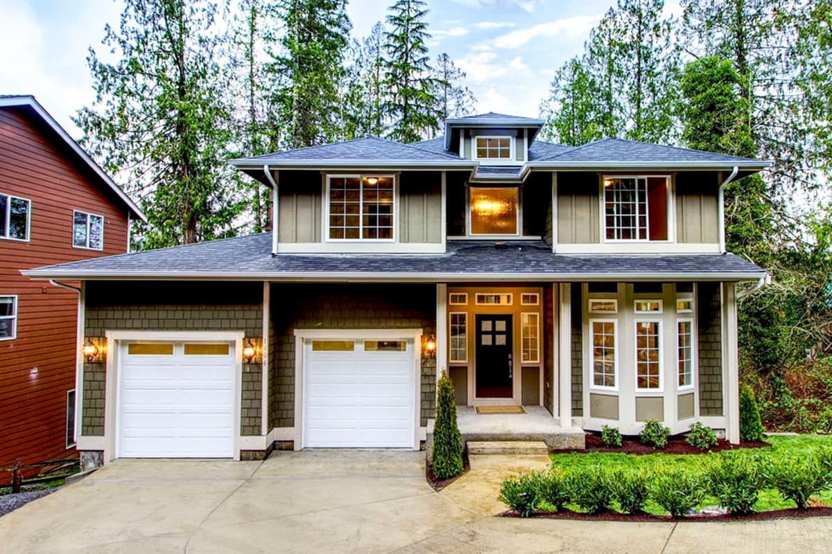 House plan exterior. Two-story home with a gabled roof. Features include a two-car garage, bay window, and a covered front porch.