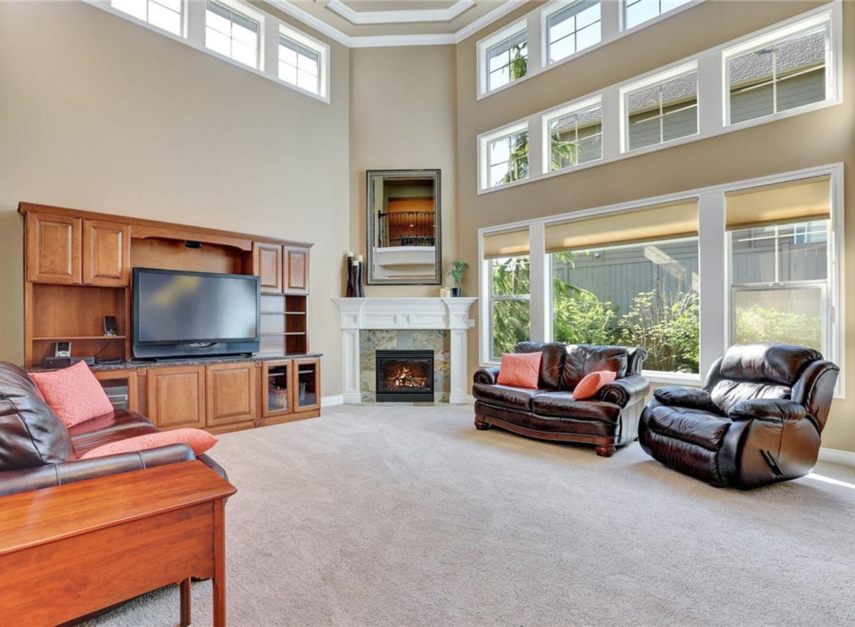 Living room with vaulted ceiling, fireplace, built-in entertainment center, and large windows.