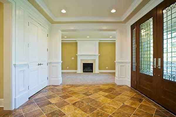 Interior view of a house, showing a fireplace, double doors with leaded glass, and wainscoting.