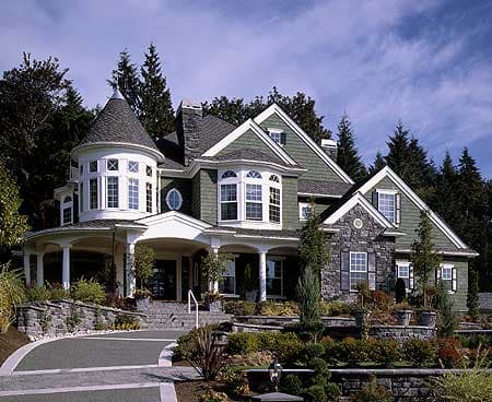 House plan exterior: Colonial Revival style home with wraparound porch, prominent turret, multiple gables, and stone accents.