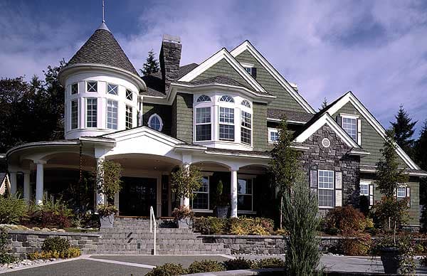 House plan exterior: Two-story home with a conical turret, bay windows, stone accents, and a covered porch with columns.