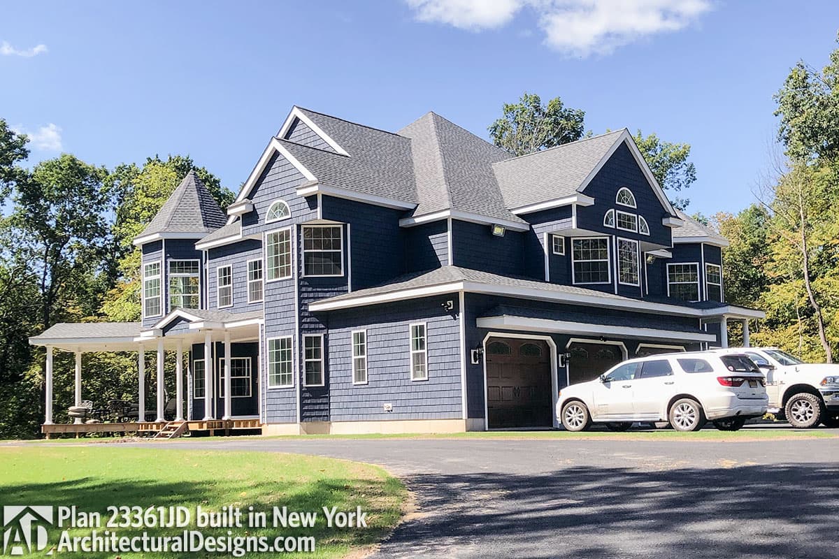 House plan exterior: Two-story home with wrap-around porch, turrets, multiple gables, and a three-car garage.