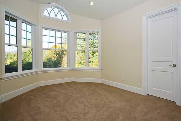Interior view of a room with bay windows, a transom window, and a paneled door.