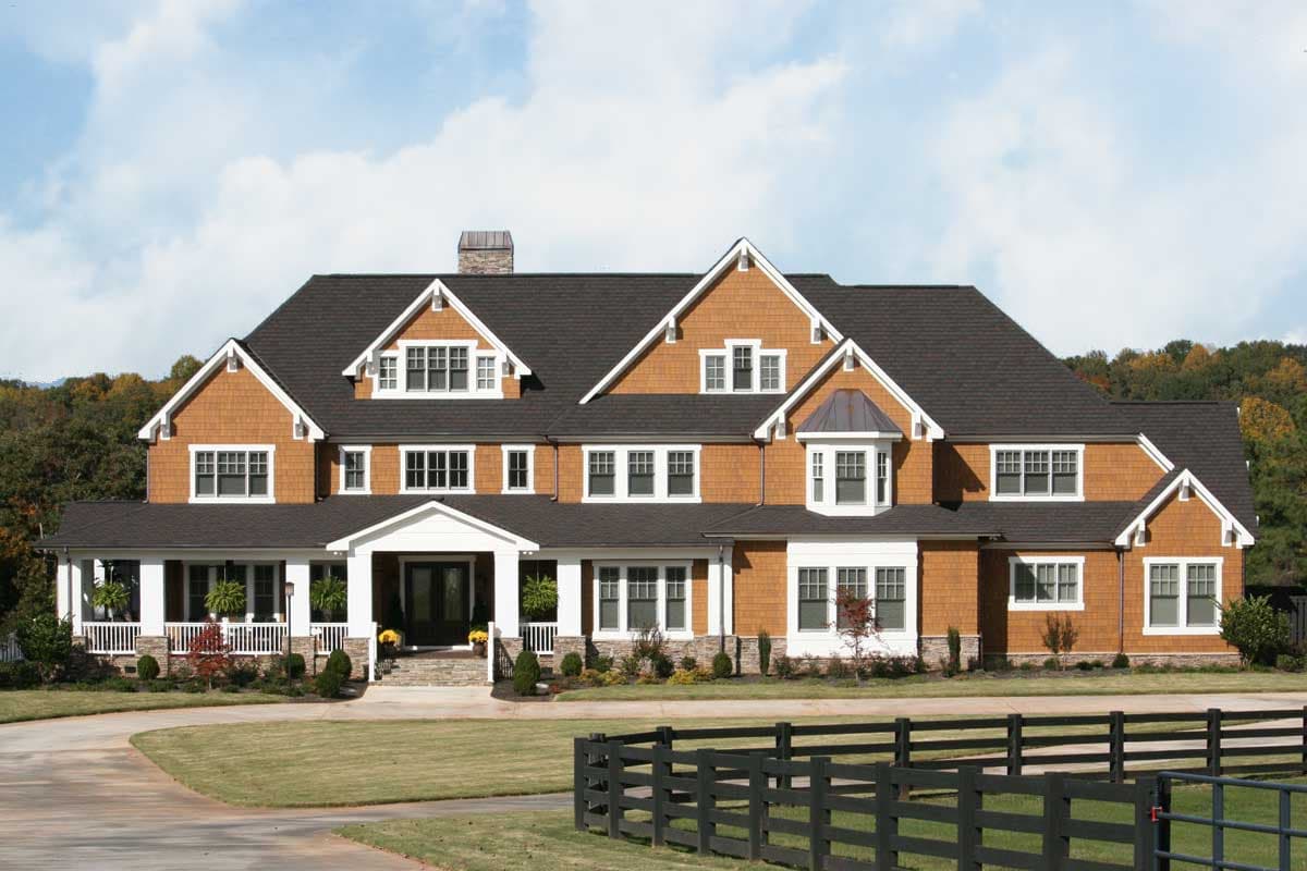 House plan exterior: This large, two-story home features a wraparound porch, multiple gables, dormer windows, and cedar shingle siding.