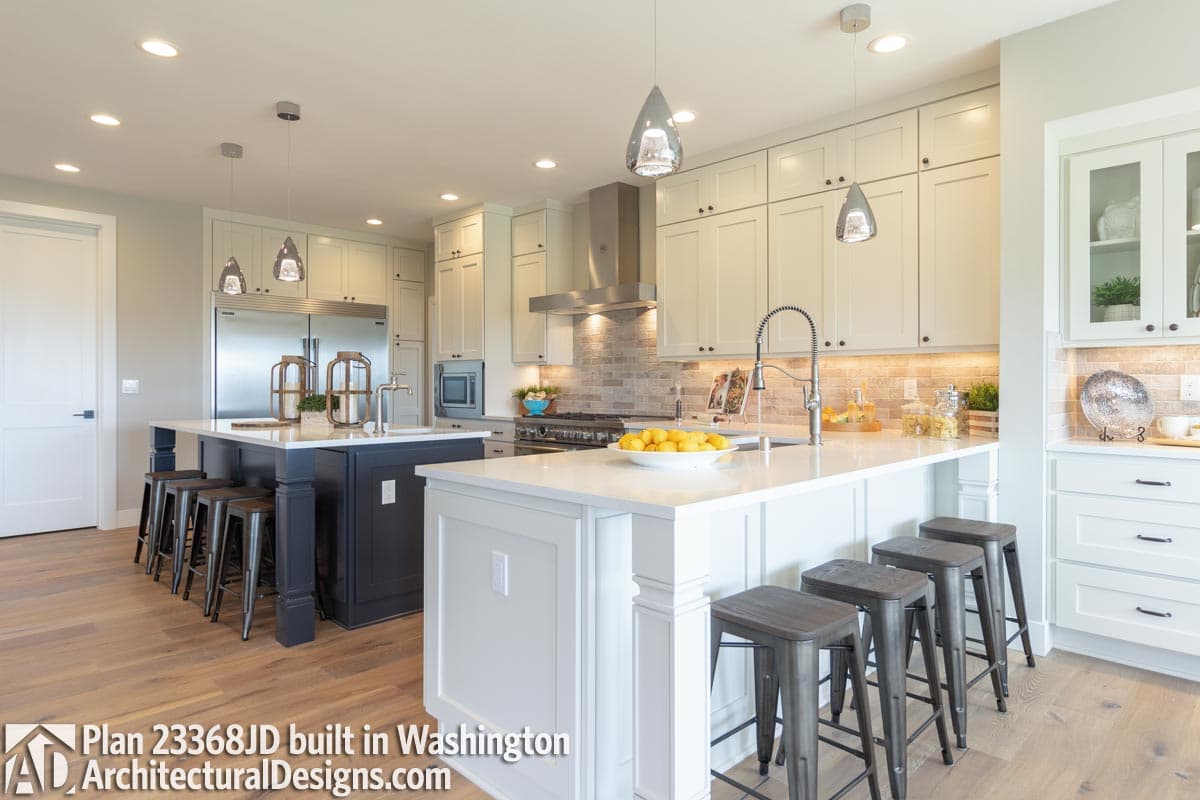 Kitchen plan with dual islands, stainless steel appliances, white cabinetry, and a brick backsplash. Plan 23368JD.